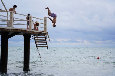 Batumi, Gürcistan - 11 Ağustos 2021: Erkekler iskeleden denize atlıyor
