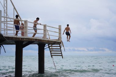 Batumi, Gürcistan - 11 Ağustos 2021: Erkekler iskeleden denize atlıyor