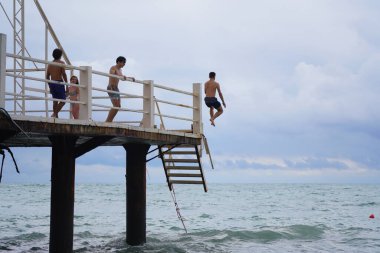 Batumi, Gürcistan - 11 Ağustos 2021: Erkekler iskeleden denize atlıyor