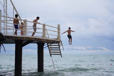 Batumi, Gürcistan - 11 Ağustos 2021: Erkekler iskeleden denize atlıyor