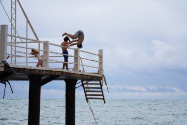 Batumi, Gürcistan - 11 Ağustos 2021: Erkekler iskeleden denize atlıyor