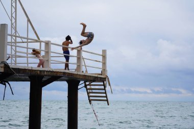 Batumi, Gürcistan - 11 Ağustos 2021: Erkekler iskeleden denize atlıyor