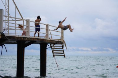 Batumi, Gürcistan - 11 Ağustos 2021: Erkekler iskeleden denize atlıyor