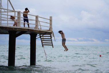 Batumi, Gürcistan - 11 Ağustos 2021: Erkekler iskeleden denize atlıyor