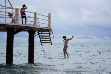 Batumi, Gürcistan - 11 Ağustos 2021: Erkekler iskeleden denize atlıyor