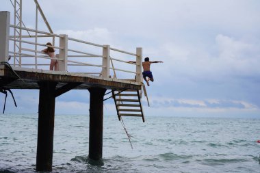 Batumi, Gürcistan - 11 Ağustos 2021: Erkekler iskeleden denize atlıyor