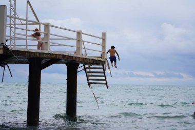 Batumi, Gürcistan - 11 Ağustos 2021: Erkekler iskeleden denize atlıyor