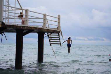Batumi, Gürcistan - 11 Ağustos 2021: Erkekler iskeleden denize atlıyor