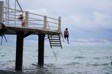 Batumi, Gürcistan - 11 Ağustos 2021: Erkekler iskeleden denize atlıyor