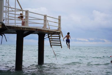 Batumi, Gürcistan - 11 Ağustos 2021: Erkekler iskeleden denize atlıyor