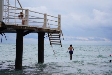 Batumi, Gürcistan - 11 Ağustos 2021: Erkekler iskeleden denize atlıyor