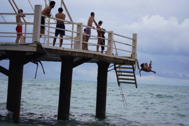 Batumi, Gürcistan - 11 Ağustos 2021: Erkekler iskeleden denize atlıyor