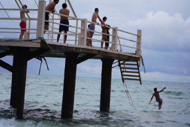 Batumi, Gürcistan - 11 Ağustos 2021: Erkekler iskeleden denize atlıyor