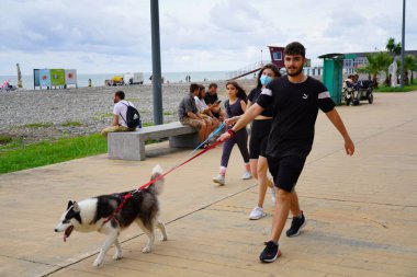 Batumi, Gürcistan - 11 Ağustos 2021: İnsanlar köpeğini toprak setinde gezdiriyorlar