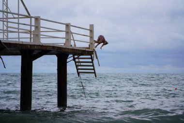Batumi, Gürcistan - 11 Ağustos 2021: Erkekler iskeleden denize atlıyor