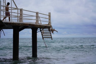 Batumi, Gürcistan - 11 Ağustos 2021: Erkekler iskeleden denize atlıyor
