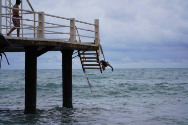 Batumi, Gürcistan - 11 Ağustos 2021: Erkekler iskeleden denize atlıyor