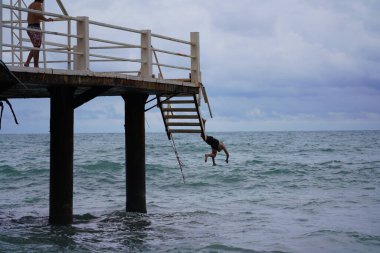 Batumi, Gürcistan - 11 Ağustos 2021: Erkekler iskeleden denize atlıyor