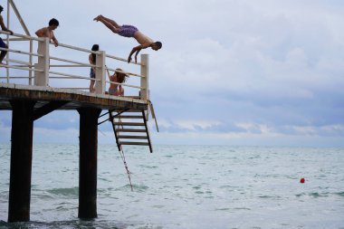 Batumi, Gürcistan - 11 Ağustos 2021: Erkekler iskeleden denize atlıyor