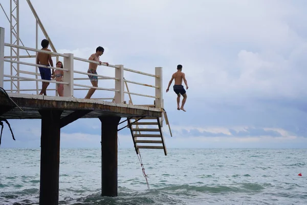 Batumi, Gürcistan - 11 Ağustos 2021: Erkekler iskeleden denize atlıyor