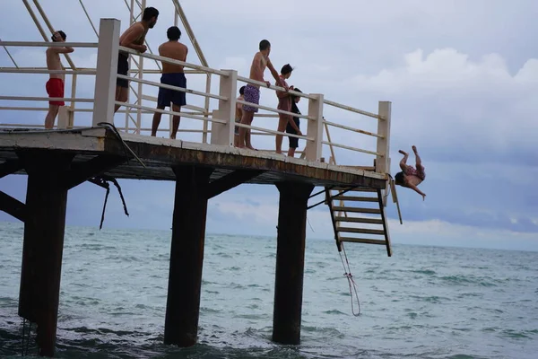 Batumi, Gürcistan - 11 Ağustos 2021: Erkekler iskeleden denize atlıyor