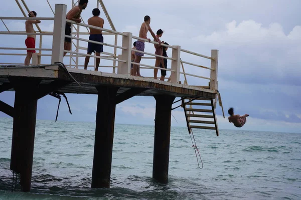 Batumi, Gürcistan - 11 Ağustos 2021: Erkekler iskeleden denize atlıyor