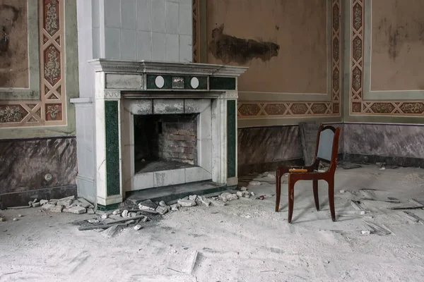 古い放棄されたマナーハウスでそれの隣にアンティークの暖炉と椅子 古いみすぼらしい汚い壁 ヴィンテージインテリア — ストック写真