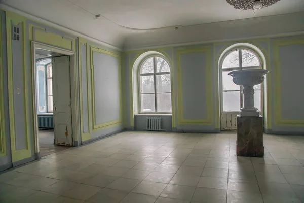 A beautiful hall with a chandelier and windows in an old abandoned manor house. Ancient architecture and interior.