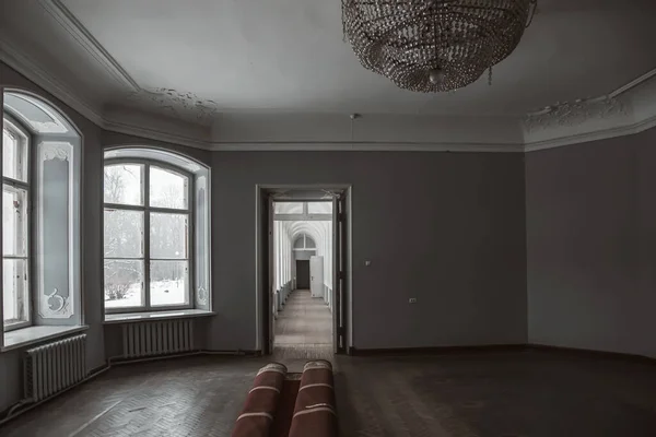 A beautiful hall with a chandelier and windows in an old abandoned manor house. Ancient architecture and interior.