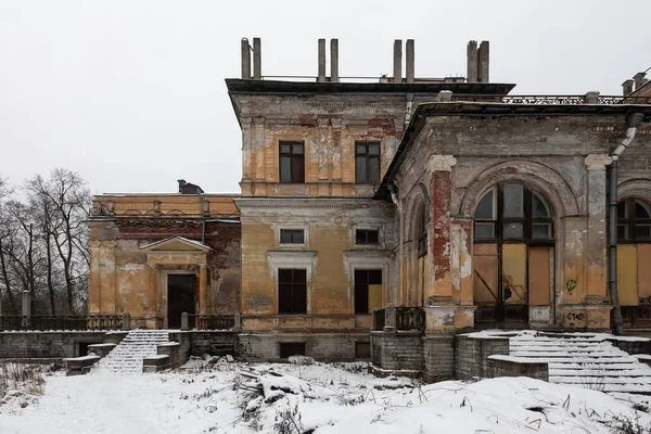 A beautiful old abandoned manor. Winter day with snow. Ancient architecture of the building.