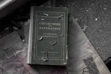 Terk edilmiş bir evin pencere eşiğinde eski bir kitap yatıyor. Pencere pervazında cam kırıkları var. Kitap Harflendirme Çevirisi - Matematiksel Analiz El Kitabı