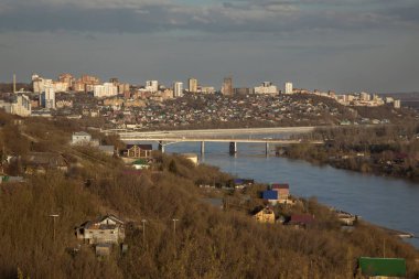 Dağdan nehre ve şehre güzel bir manzara. Nehir kıyısındaki şehir. Akşam sıcacık güneş ışığı. Mavi gökyüzü.