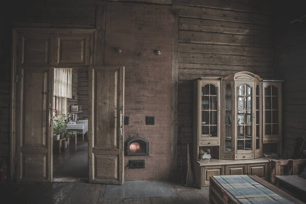 Beautiful and vintage interior of an old village house. Wooden cabinet. A door. Wooden walls. Reflection of windows in the closet. Old stove.