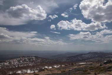 Mavi gökyüzünün altındaki güzel dağ manzarası. Dağların yamaçlarında kar var. Güzel doğa..