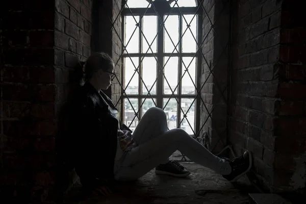 窓の近くに座っている少女のシルエット 窓のある古代の部屋 放棄された家 美しい少女のシルエット 窓の光 — ストック写真