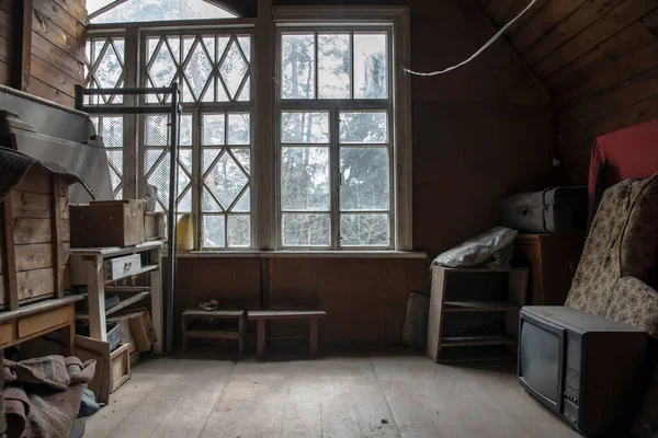 An old room in an abandoned house. TV and old boxes with things. Big window. Wooden walls and floor. Translation of the inscription on the boxes - furniture inside.