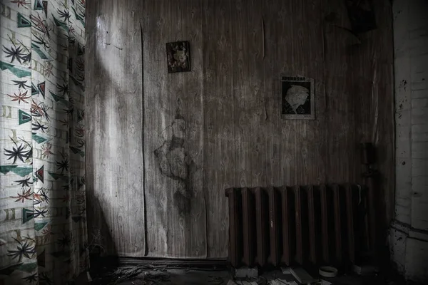 Scary old room in an abandoned house. Old magazine pages hang on the wall. Shabby walls. Gloomy atmosphere. Translation of the inscription on the wall - Crocodile Magazine 1979.