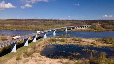 Büyük bir nehrin üzerinde uzun ve yüksek bir köprü. Güzel doğa. Güneşli bir gün. Güzel mimari. Renkli fotoğraf.