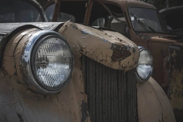 Headlights and old front of an abandoned car. Old rusty car. A beautiful element of an abandoned car.