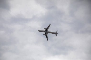 Gökyüzünde güzel bir yolcu uçağı uçuyor. Gri bulutlar. Hava gösterisinde yeni yolcu uçağı.