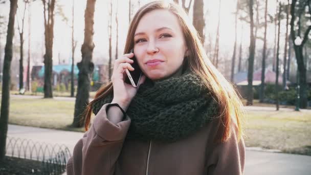 Девушка разговаривает по телефону в парке — стоковое видео