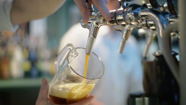 Close-up de mão barman na torneira de cerveja derramando uma cerveja lager calado — Vídeo de Stock
