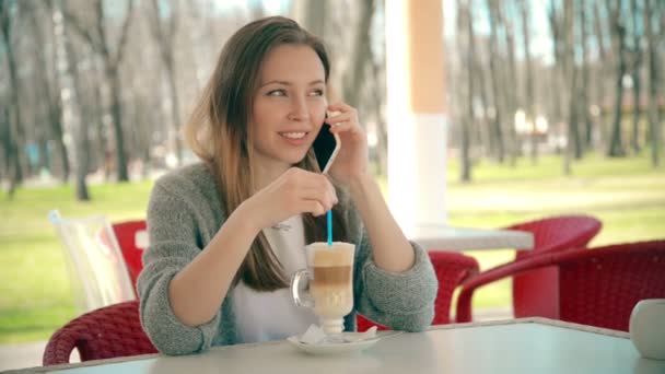 Mujer hablando por teléfono inteligente bebiendo café riendo en la cafetería. Hermosa. — Vídeos de Stock