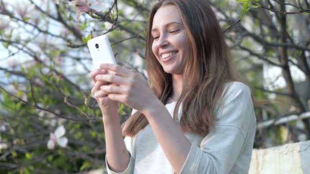 Mujer usando la aplicación en el teléfono inteligente sonriendo y mensajes de texto en el teléfono móvil — Vídeo de stock