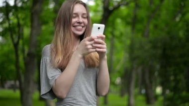 Güzel kadın hücre smartphone açık havada park - ayrıntı kullanır