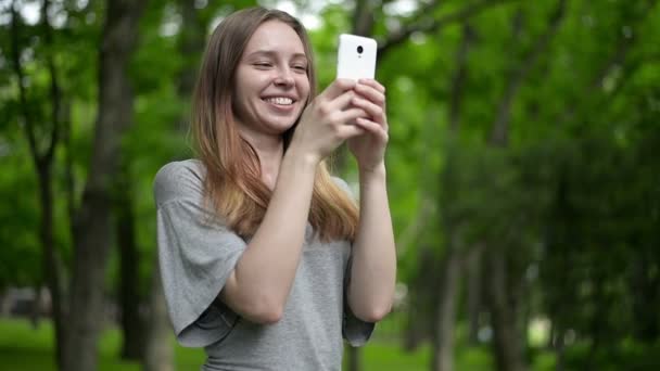 Hermosa mujer utiliza teléfono inteligente celular al aire libre en el parque - detalle — Vídeos de Stock