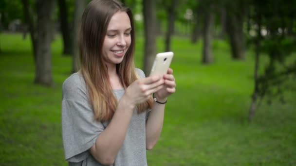 Hermosa mujer utiliza teléfono inteligente celular al aire libre en el parque - detalle — Vídeo de stock