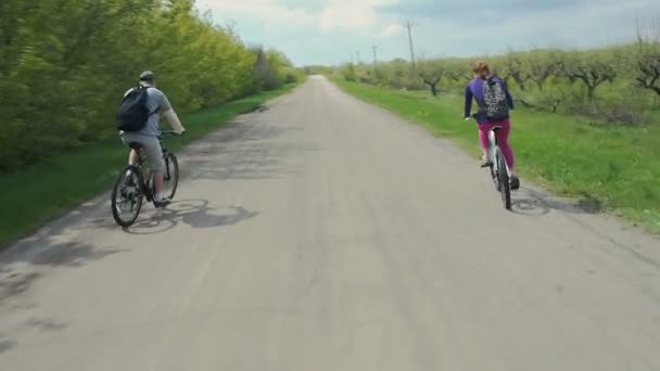 Fiatal pár kerékpárral boldogan együtt egy napos park utca — Stock videók