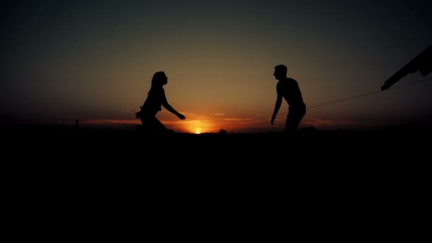 Homem joga uma mulher no por do sol e para baixo — Vídeo de Stock