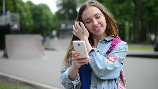 Mädchen mit dem Handy vor der Kulisse des Rollerparks — Stockvideo